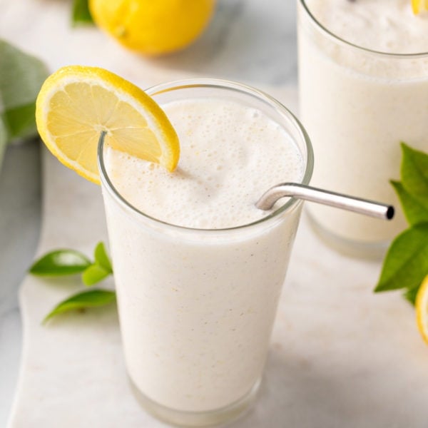 Glass of frosted lemonade garnished with a lemon slice.