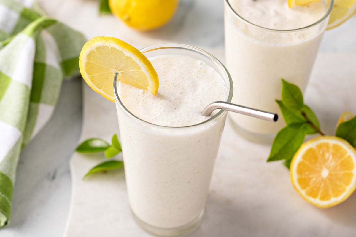 Angled view of the top of a glass of frosted lemonade garnished with a lemon slice.