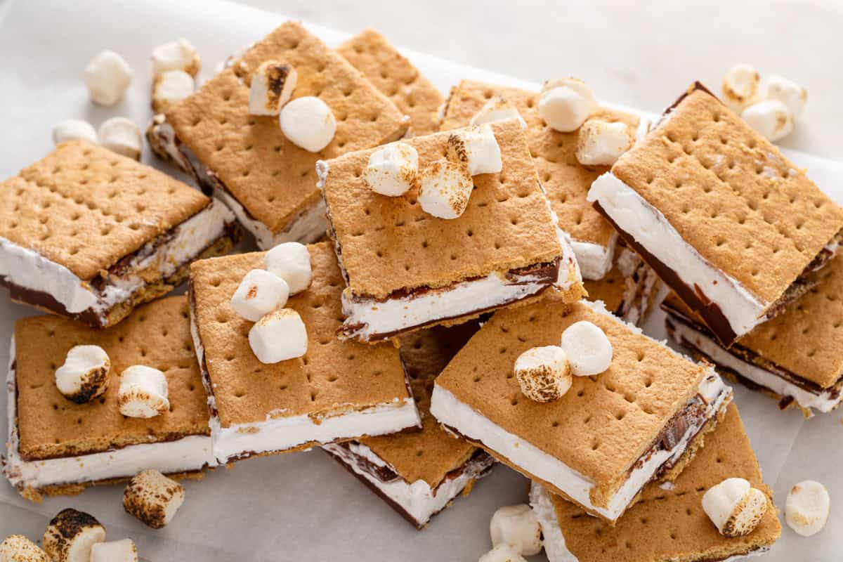Frozen s'mores arranged in a pile on a piece of parchment paper.