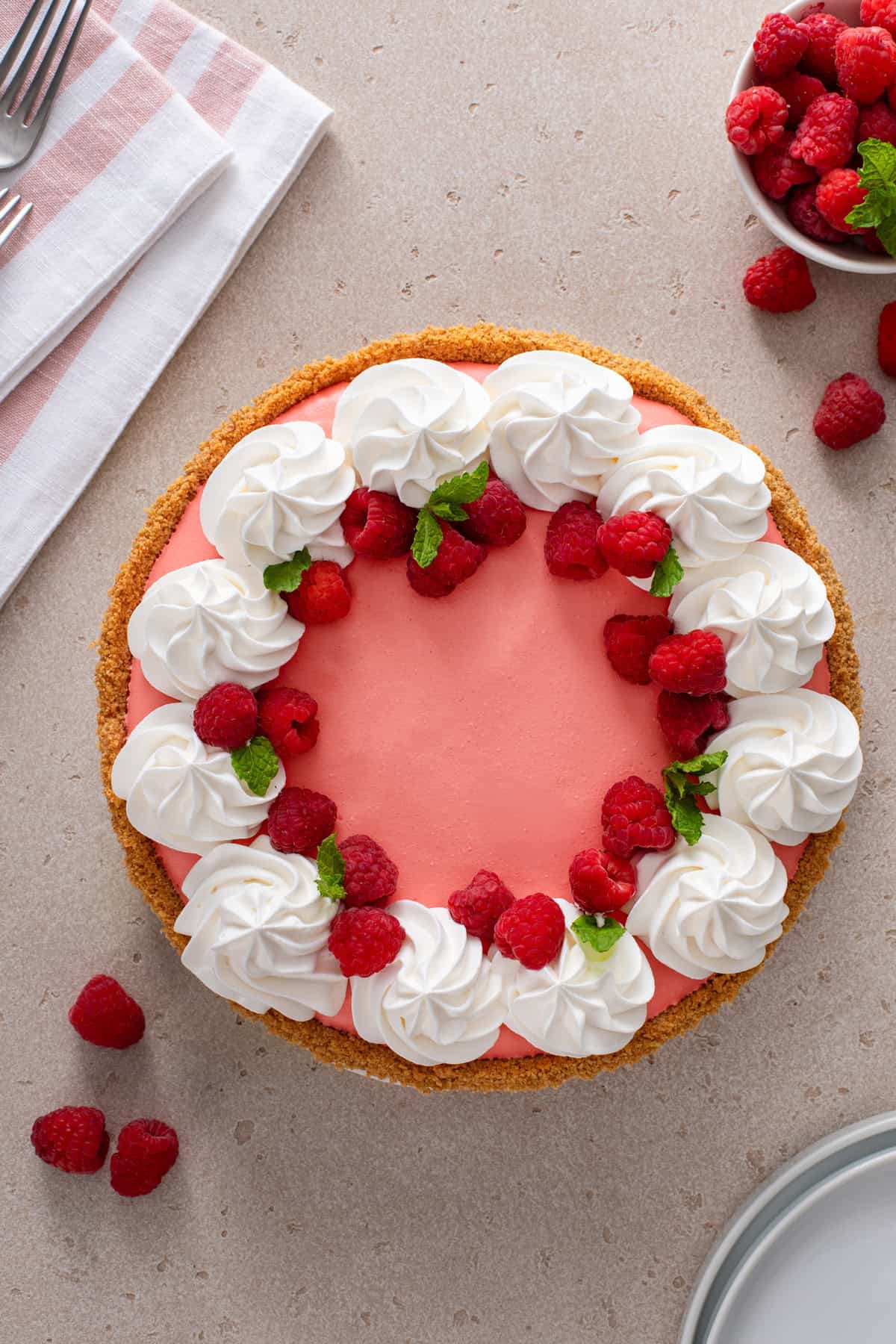 Overhead view of raspberry jello pie garnished with whipped cream and fresh raspberries.
