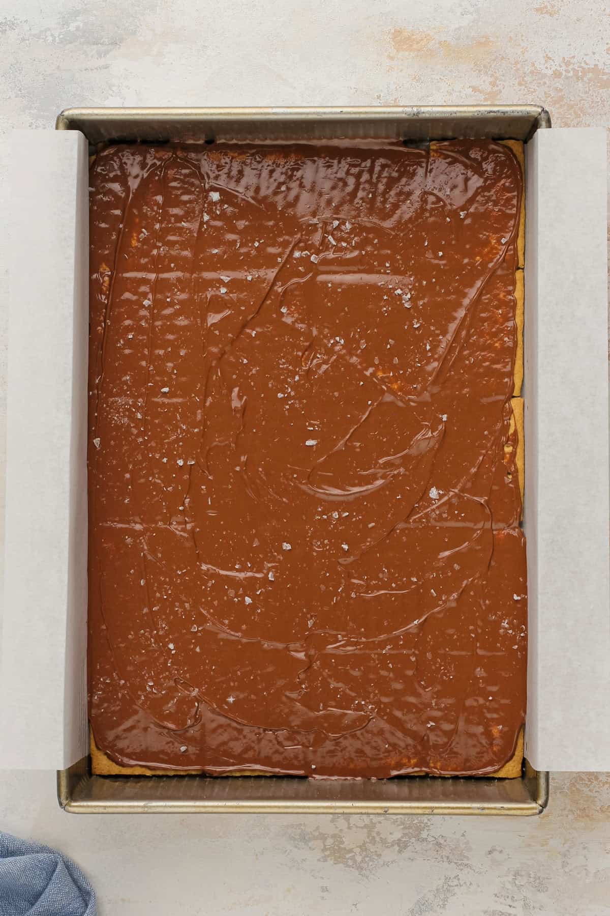Melted chocolate spread over graham crackers in a baking pan.