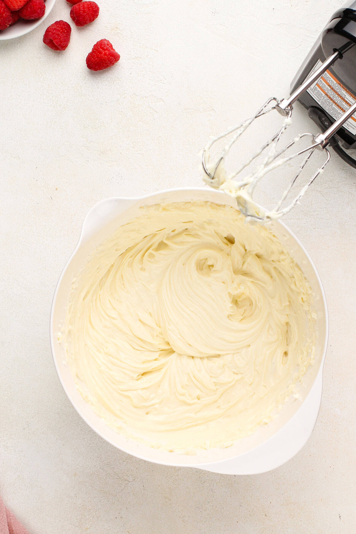 Cream cheese mixed with sugar and vanilla in a white bowl.