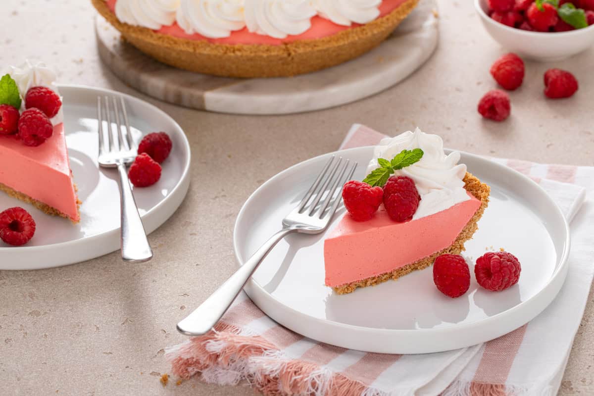 Two white plates, each holding a fork and a slice of raspberry jello pie.