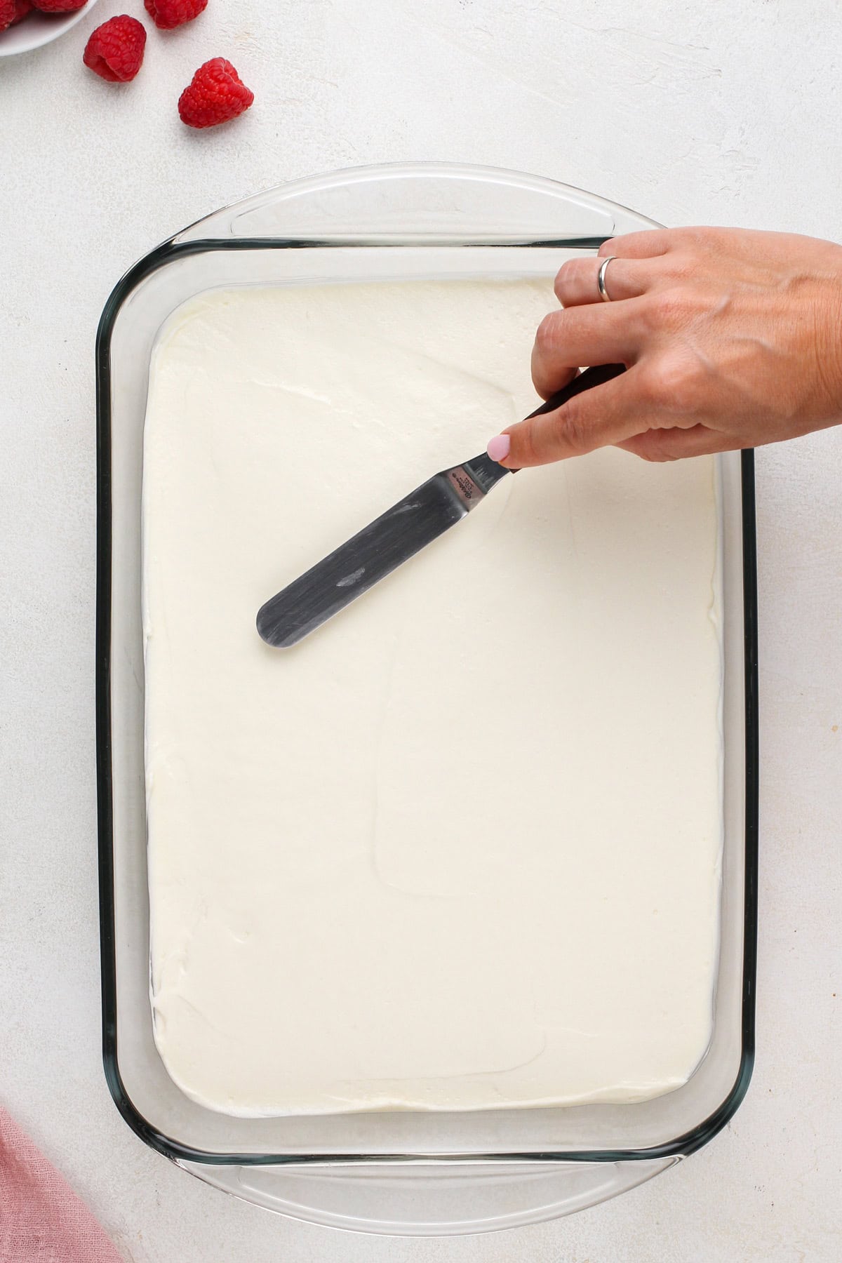 Cream cheese filling being spread over pretzel crust.