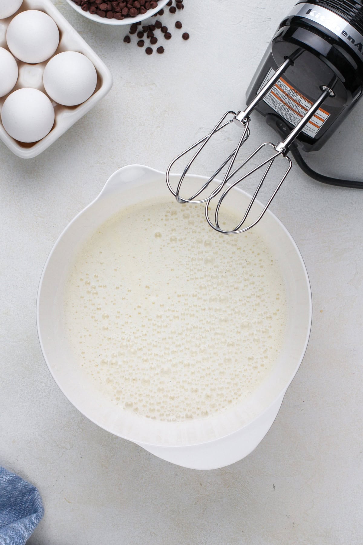 Beaten voluminous eggs in a white bowl.