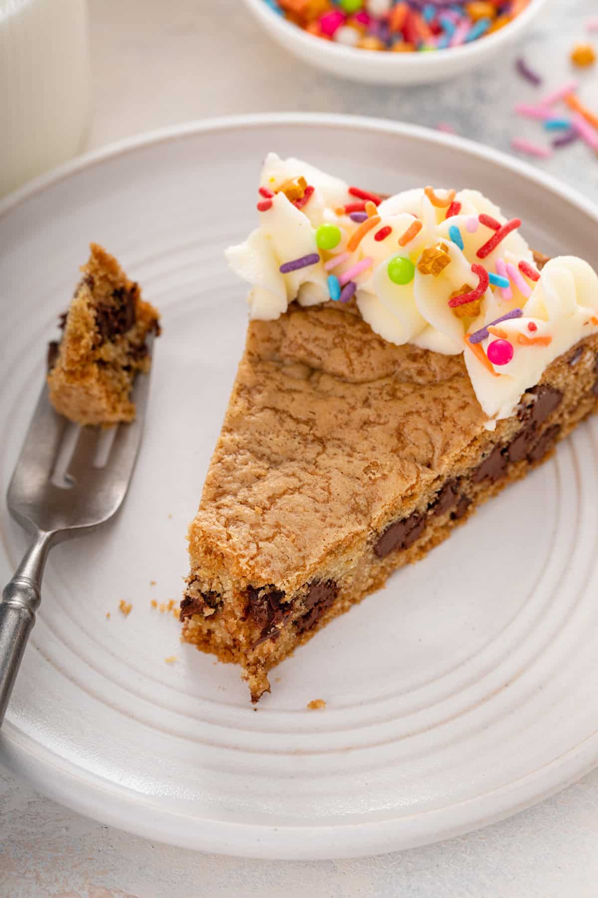 Plated slice of chocolate chip cookie cake with a bite cut from the end.
