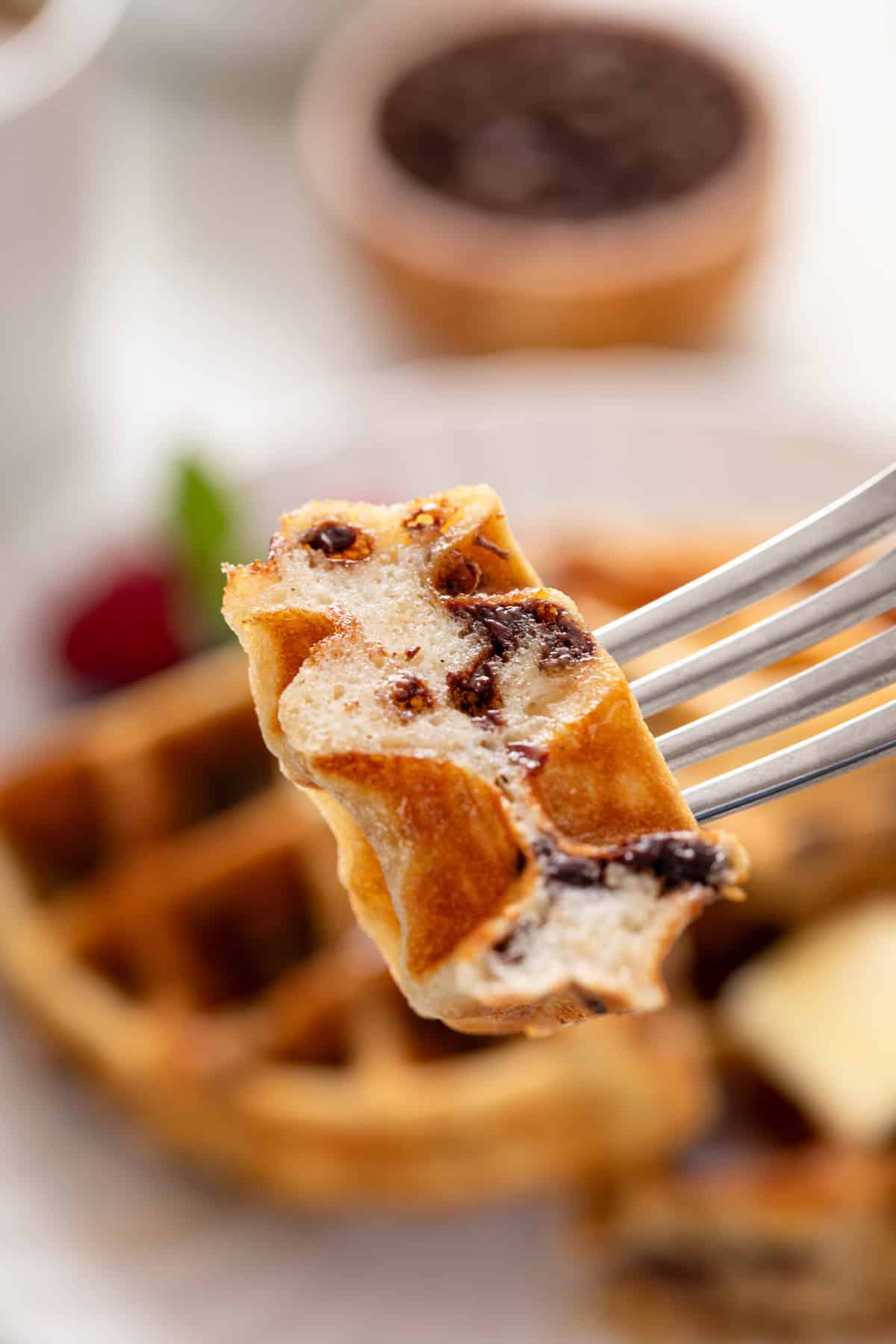 Bite of chocolate chip waffle on a fork.