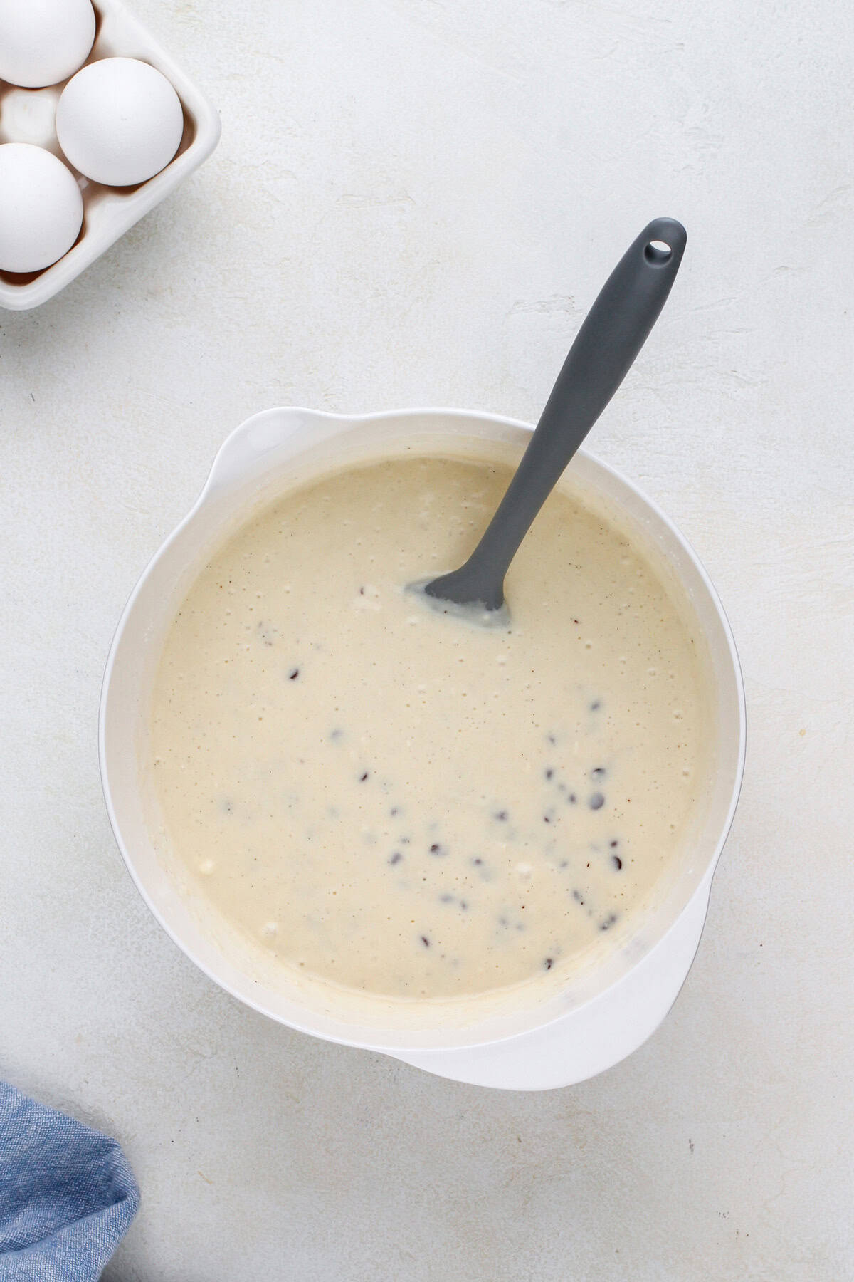 Chocolate chip waffle batter in a white bowl.