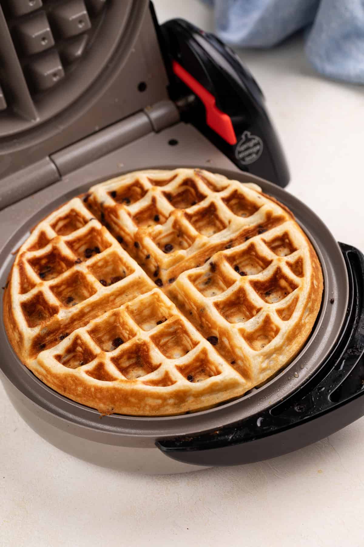 Cooked chocolate chip waffle in a waffle iron.