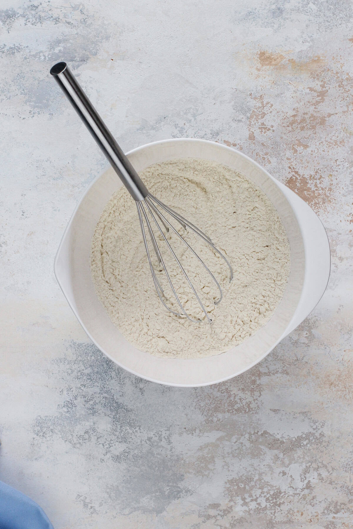 Dry ingredients for chocolate chip cookie cake whisked in a white bowl.