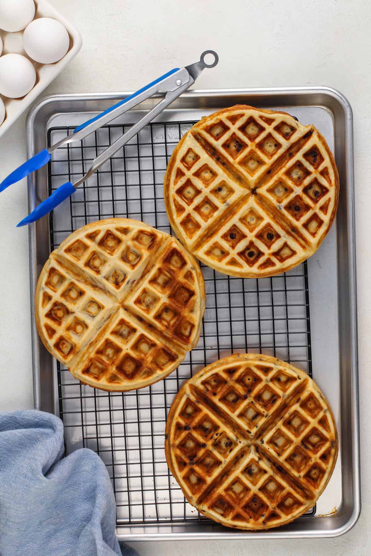 Cooked chocolate chip waffles on a wire cooling rack.