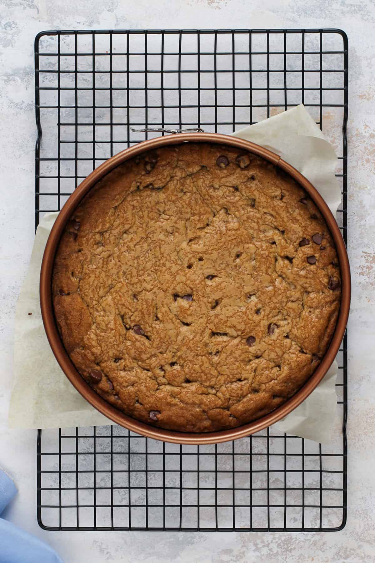 Cooling chocolate chip cookie cake on a wire rack.