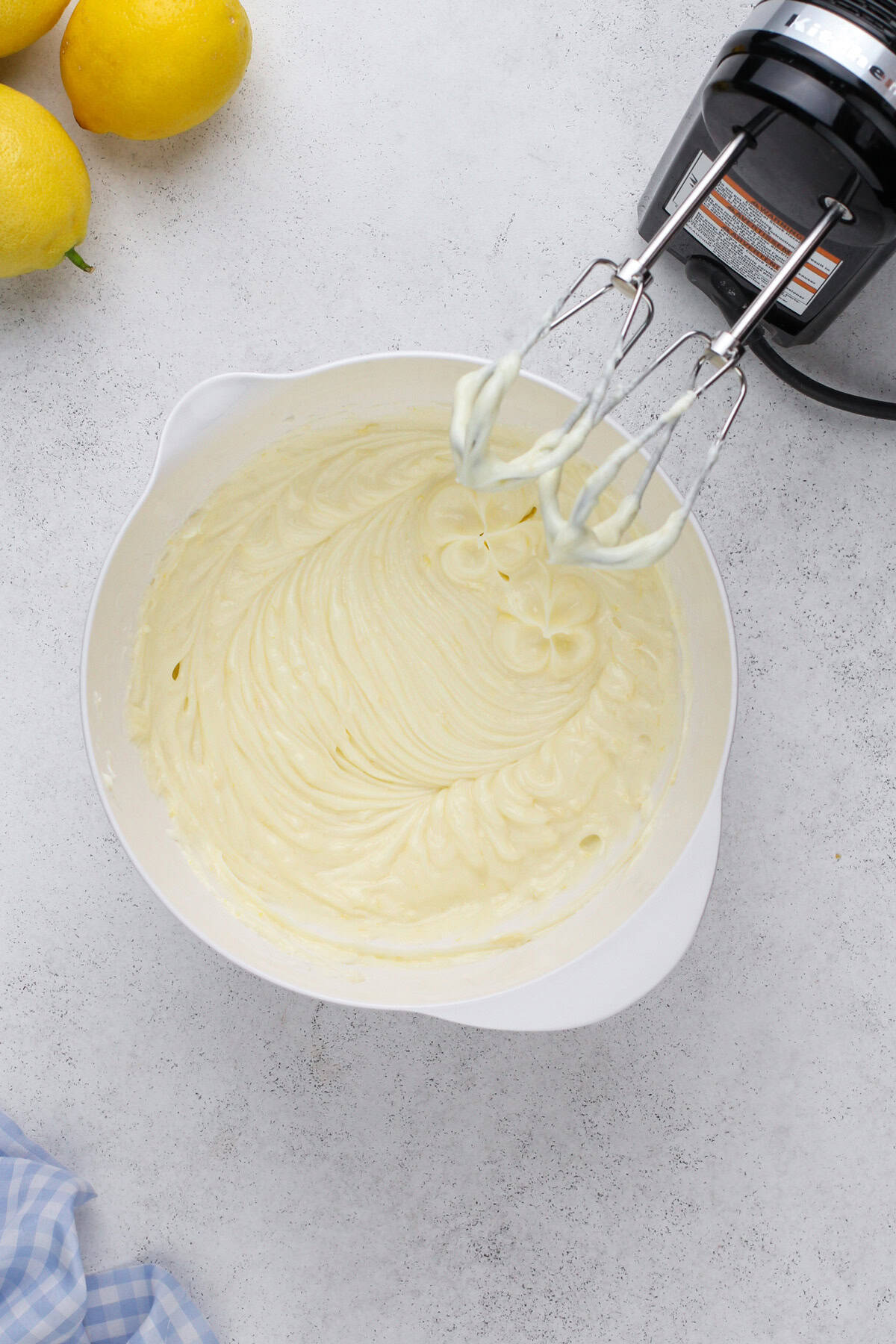 Cream cheese mixed with sugar and eggs in a white bowl.