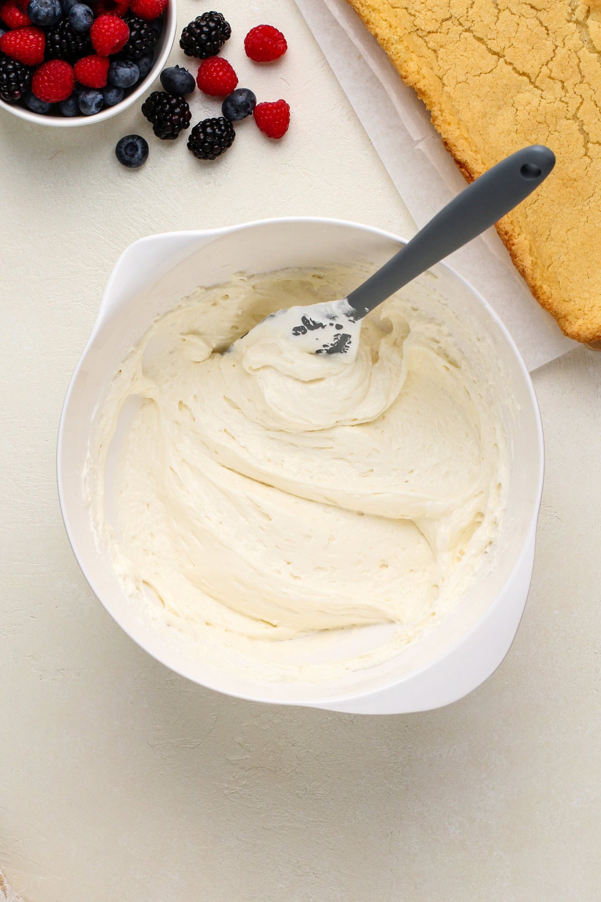 Cream cheese filling for fruit pizza mixed in a white bowl.