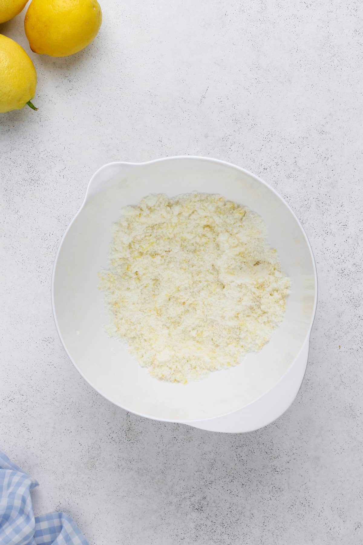 Granulated sugar mixed with lemon zest in a white bowl.