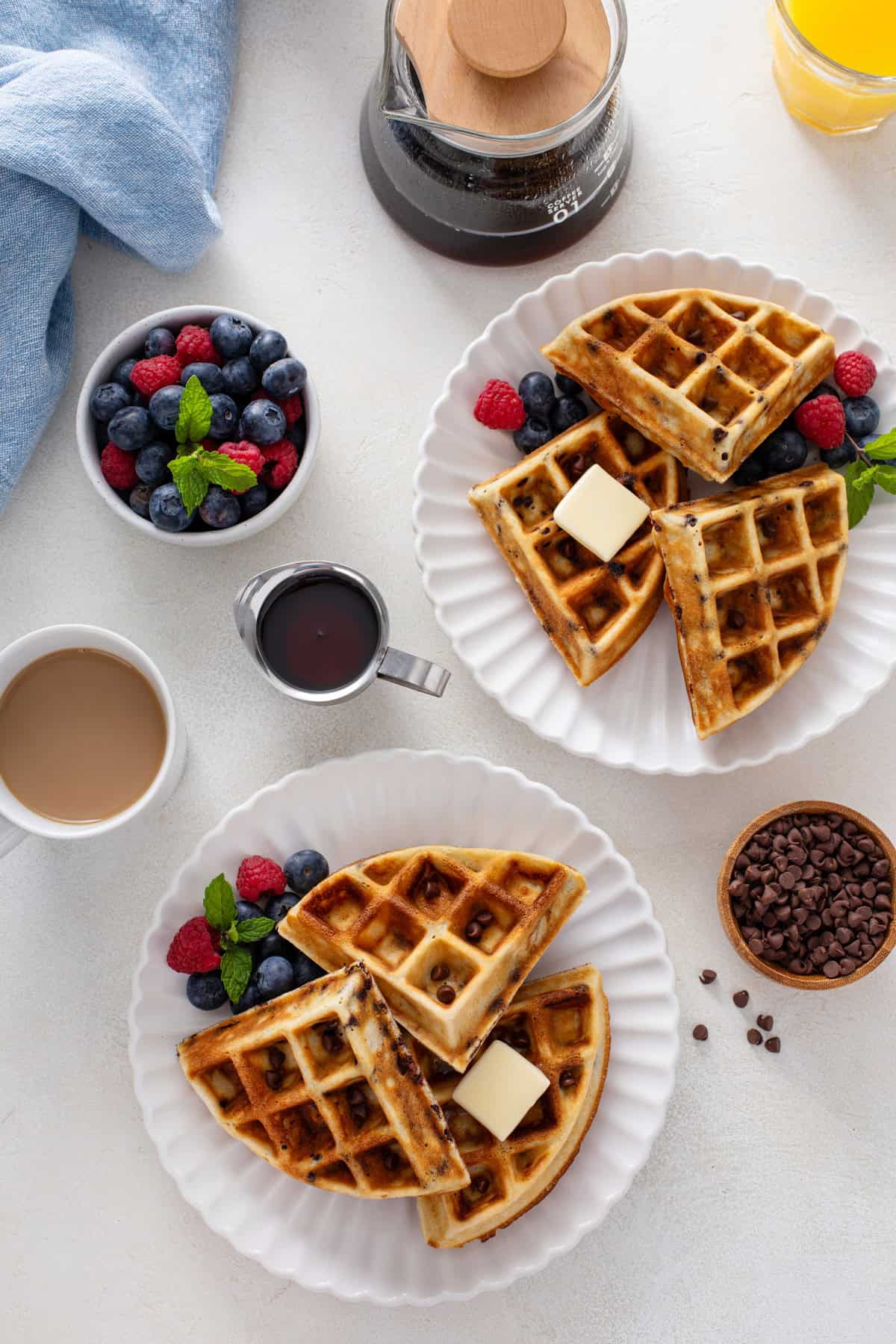 Overhead view of chocolate chip waffles on white plates.