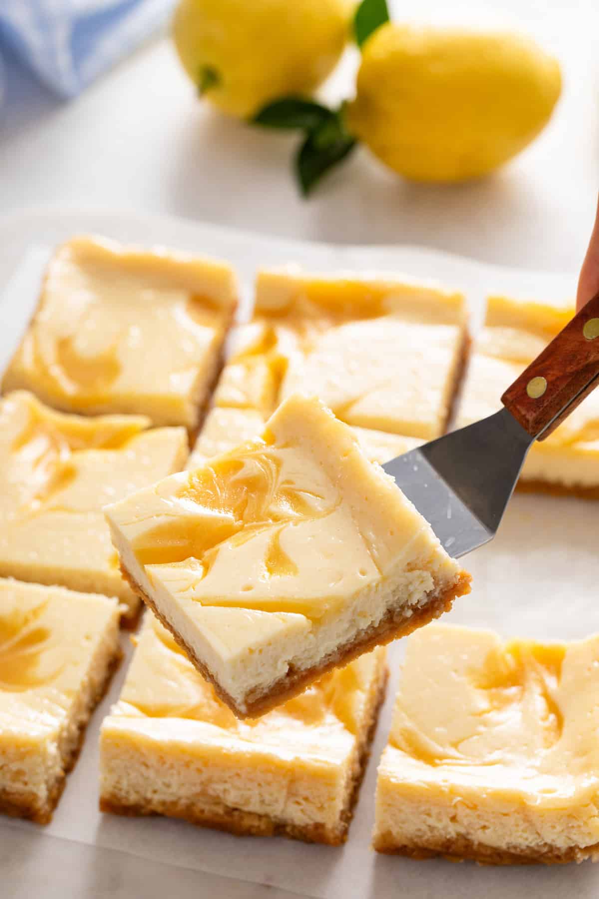 Cake server lifting up a sliced lemon cheesecake bar.