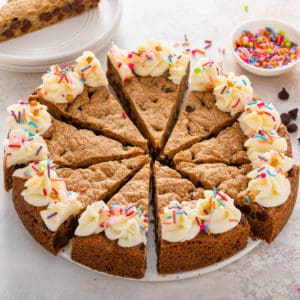 Sliced chocolate chip cookie cake topped with frosting and sprinkles.