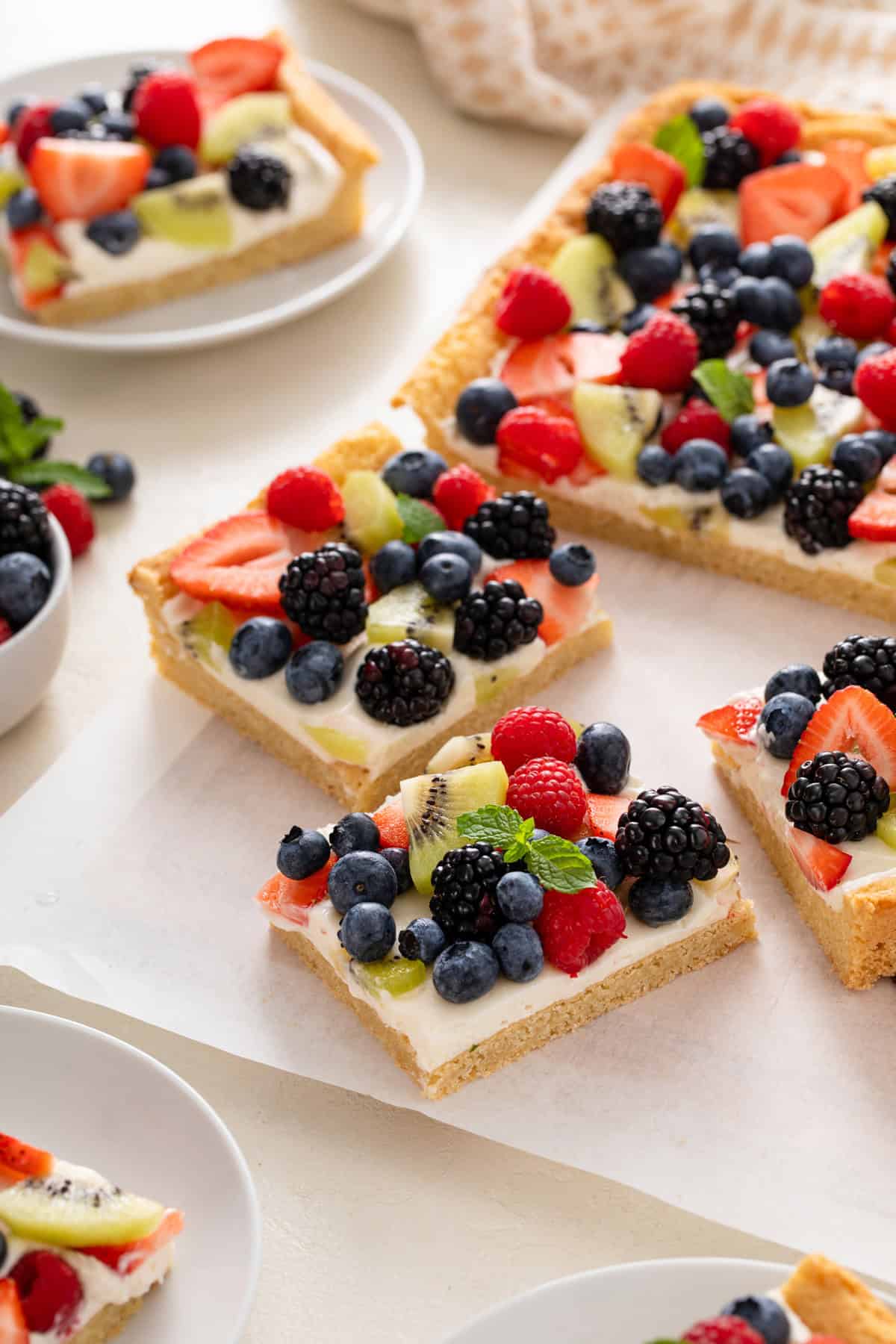 Sliced fruit pizza arranged on a sheet of parchment paper.