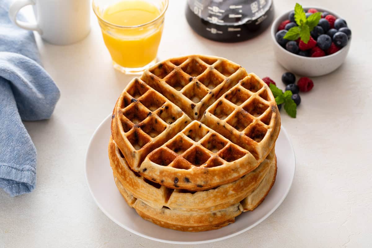Stack of chocolate chip waffles on a white plate.