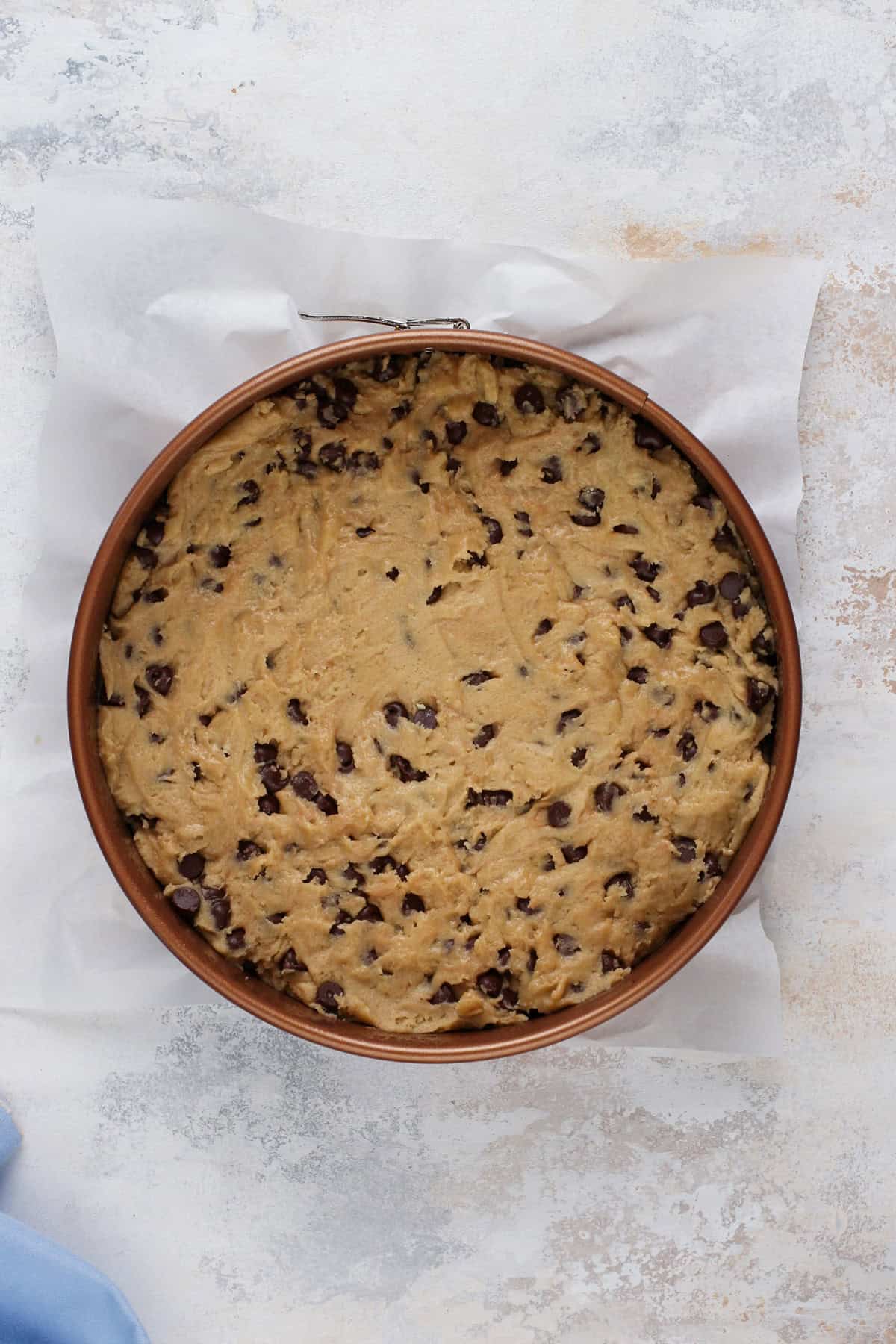 Unbaked chocolate chip cookie cake in a springform pan, ready to go in the oven.
