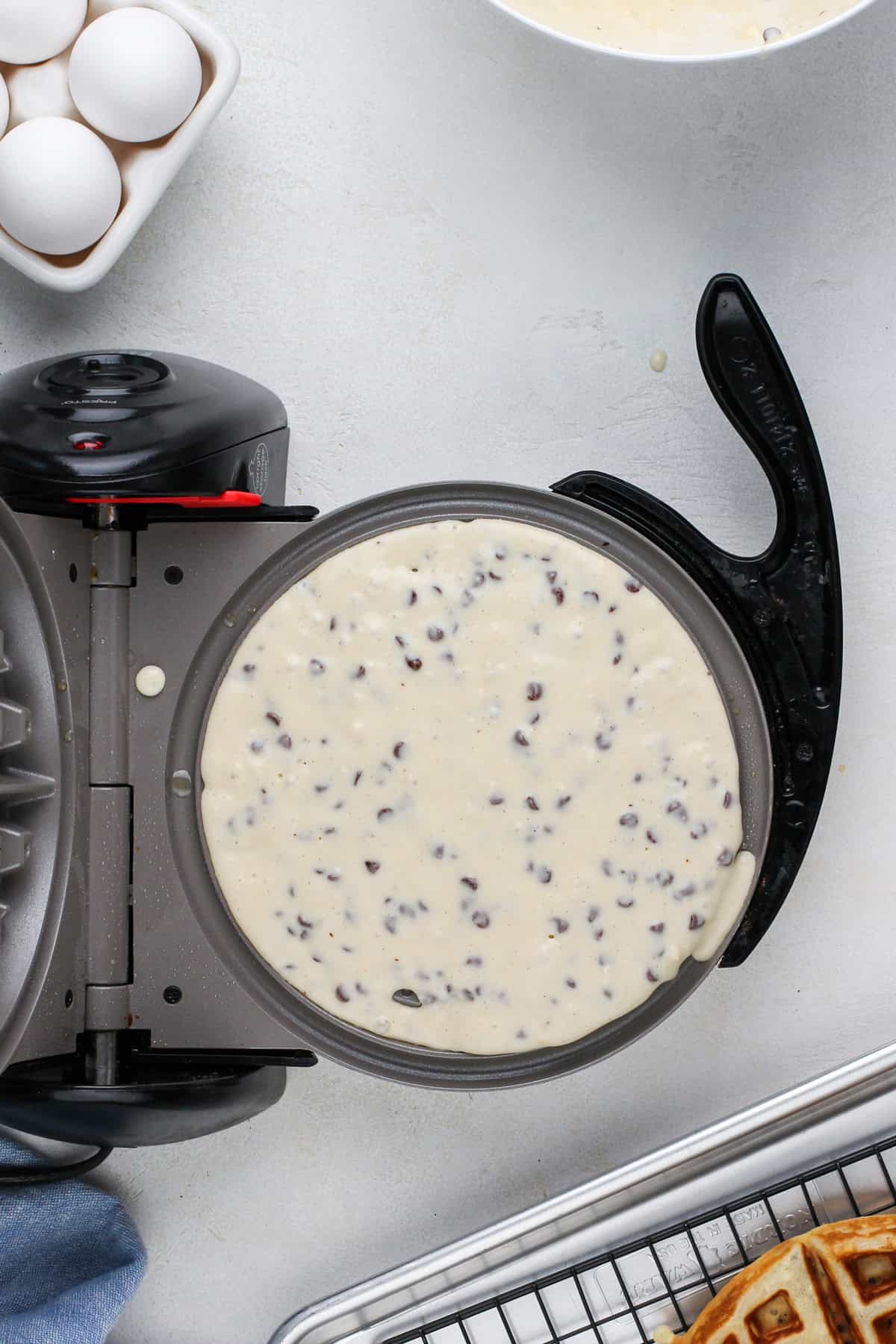 Chocolate chip waffle batter poured into a waffle iron.