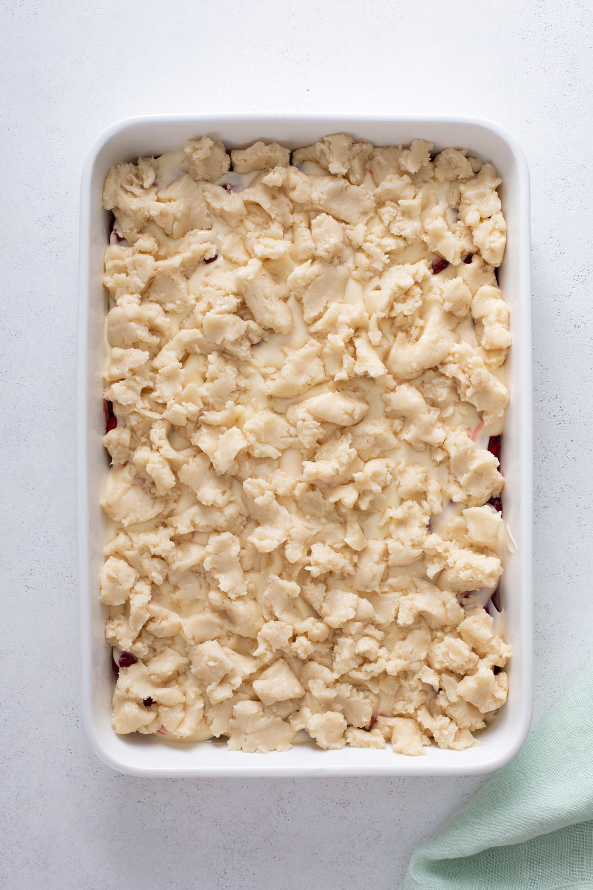 Assembled cherry cheesecake cake in a baking dish, ready to go in the oven.