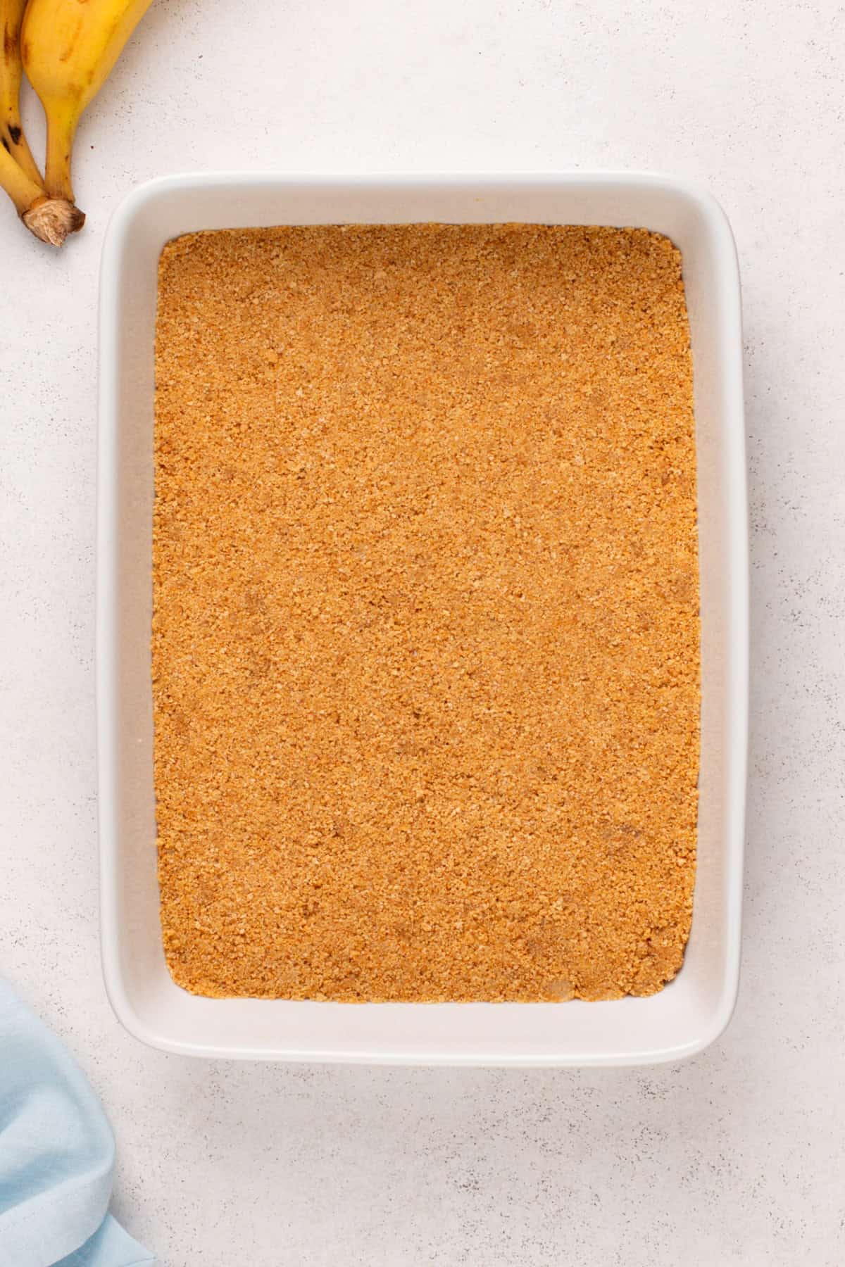 Graham cracker crust pressed into a white baking dish.
