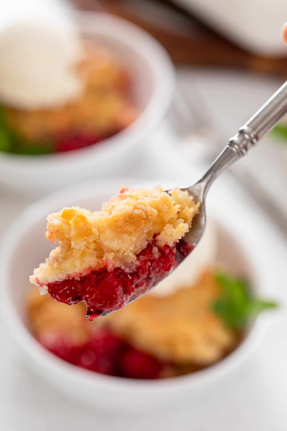 Bite of cherry cheesecake cake on a spoon.