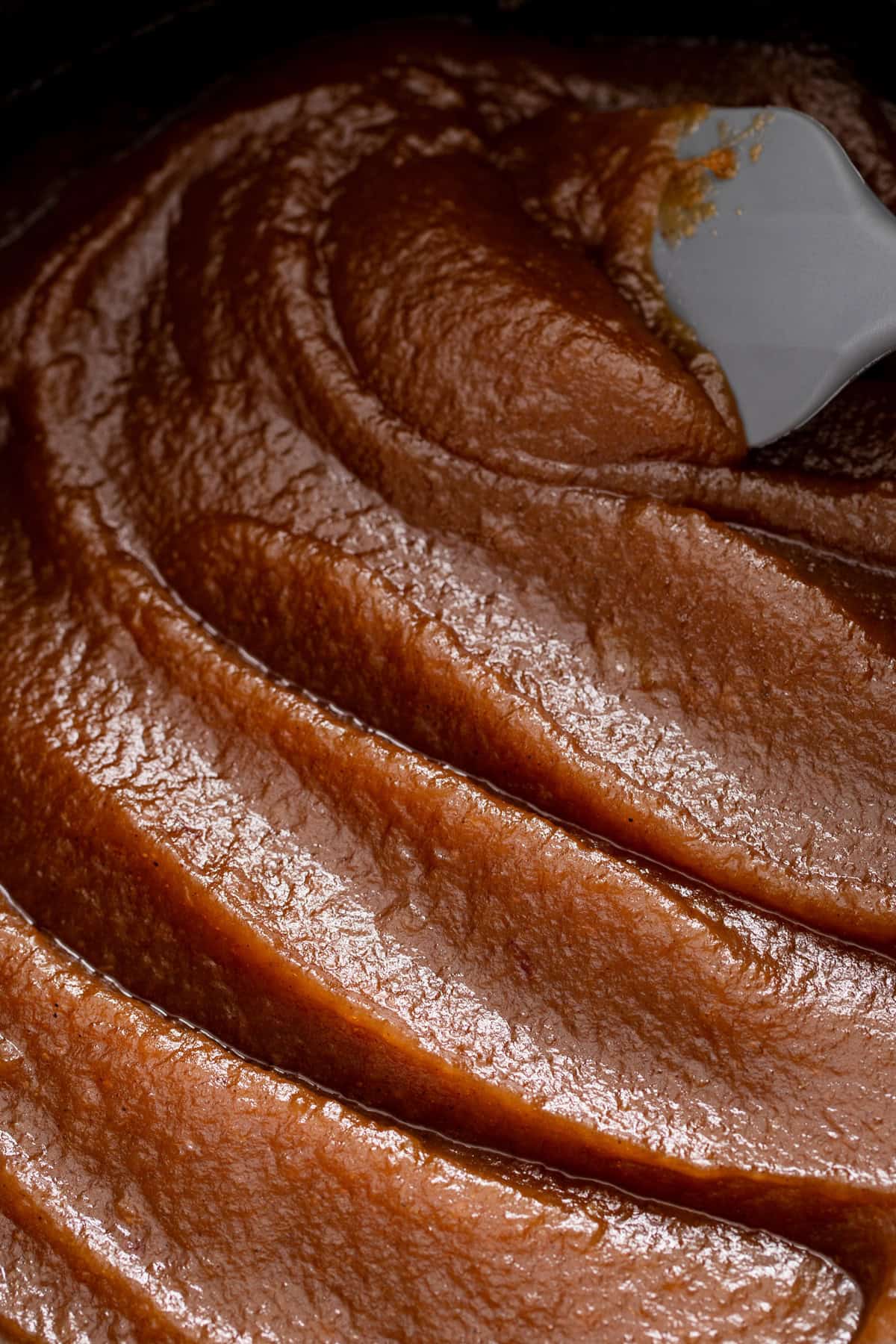 Close up of spoon running through cooked apple butter.