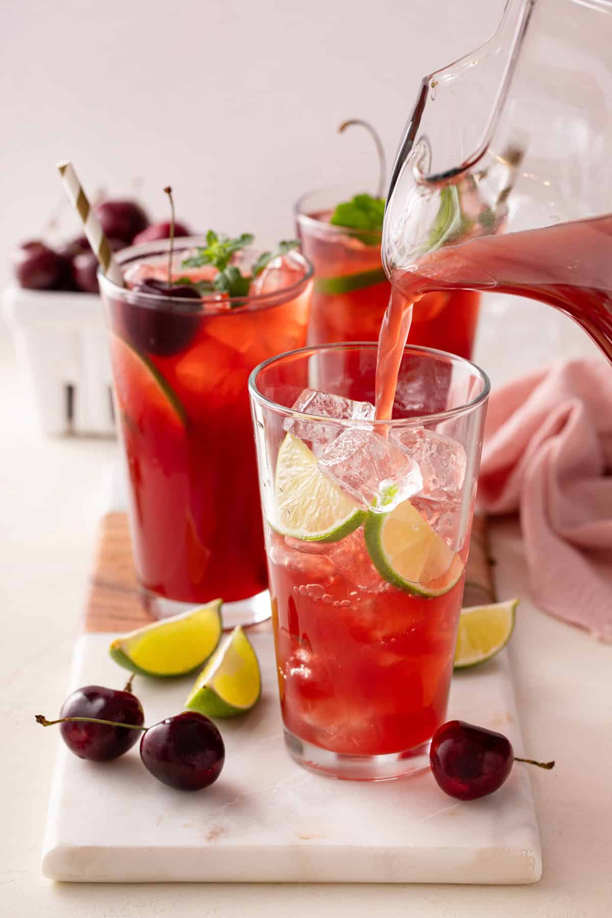 Cherry limeade being poured into a glass over ice.