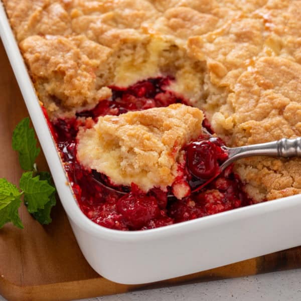 Spoon serving cherry cheesecake cake out of a pan.