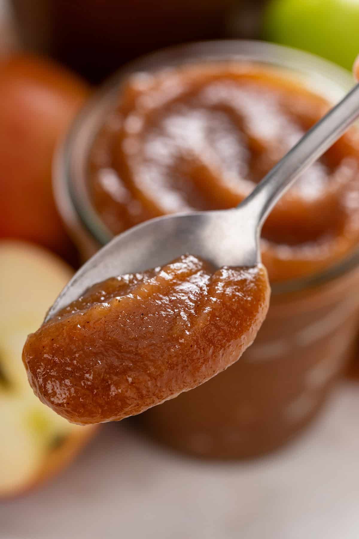 Spoon holding up a bite of stovetop apple butter to the camera.