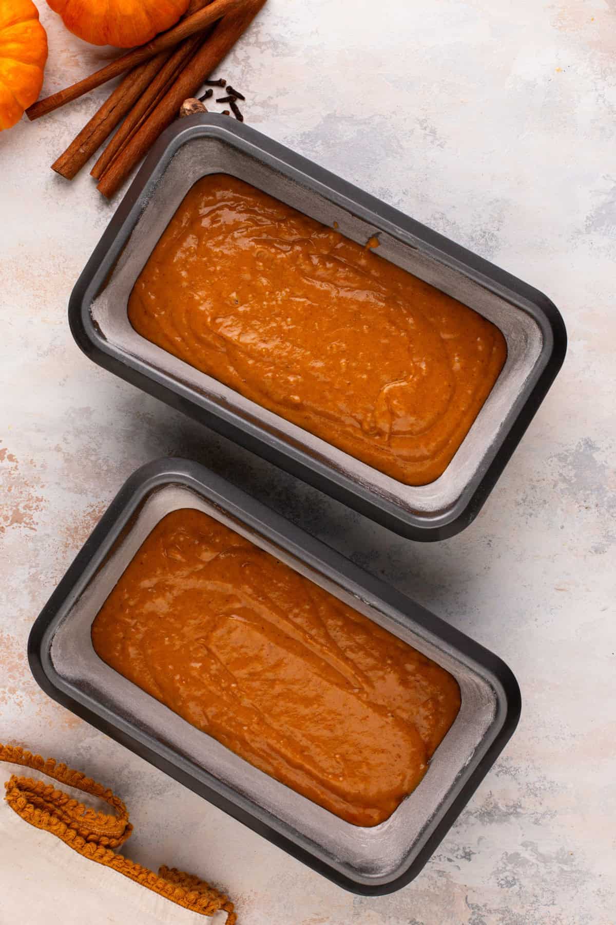 Base layer of pumpkin bread batter in the bottom of two loaf pans.
