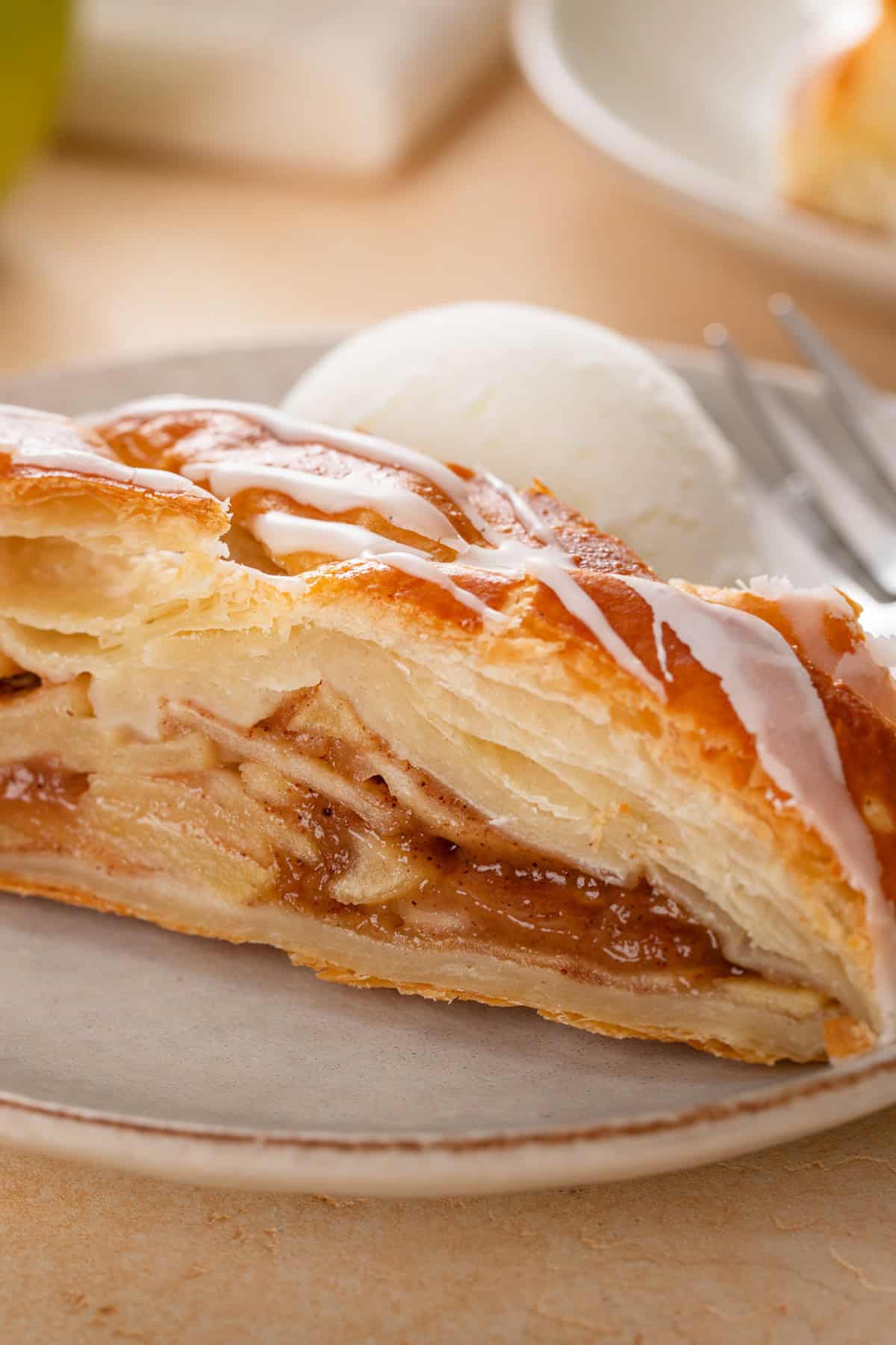 Close up image of a slice of apple strudel with a scoop of ice cream on a plate.