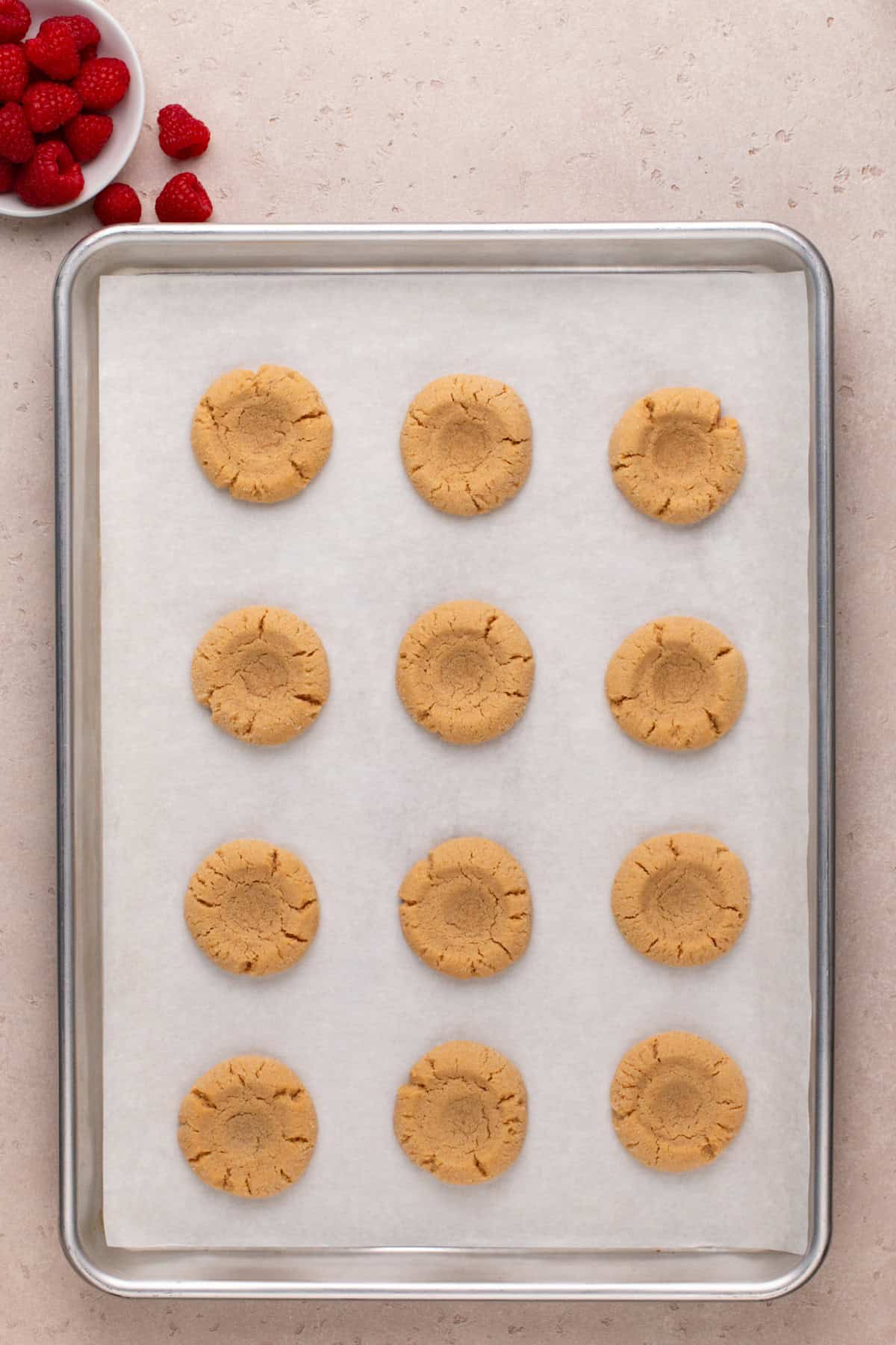Partially baked peanut butter and jelly cookies on a baking sheet.