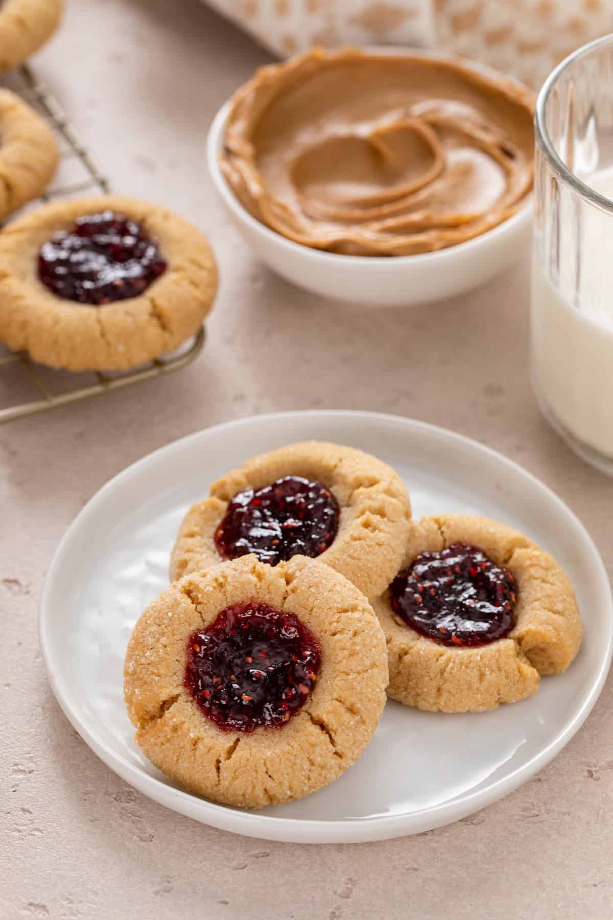 Close up of three peanut butter and jelly cookies on a white plate.