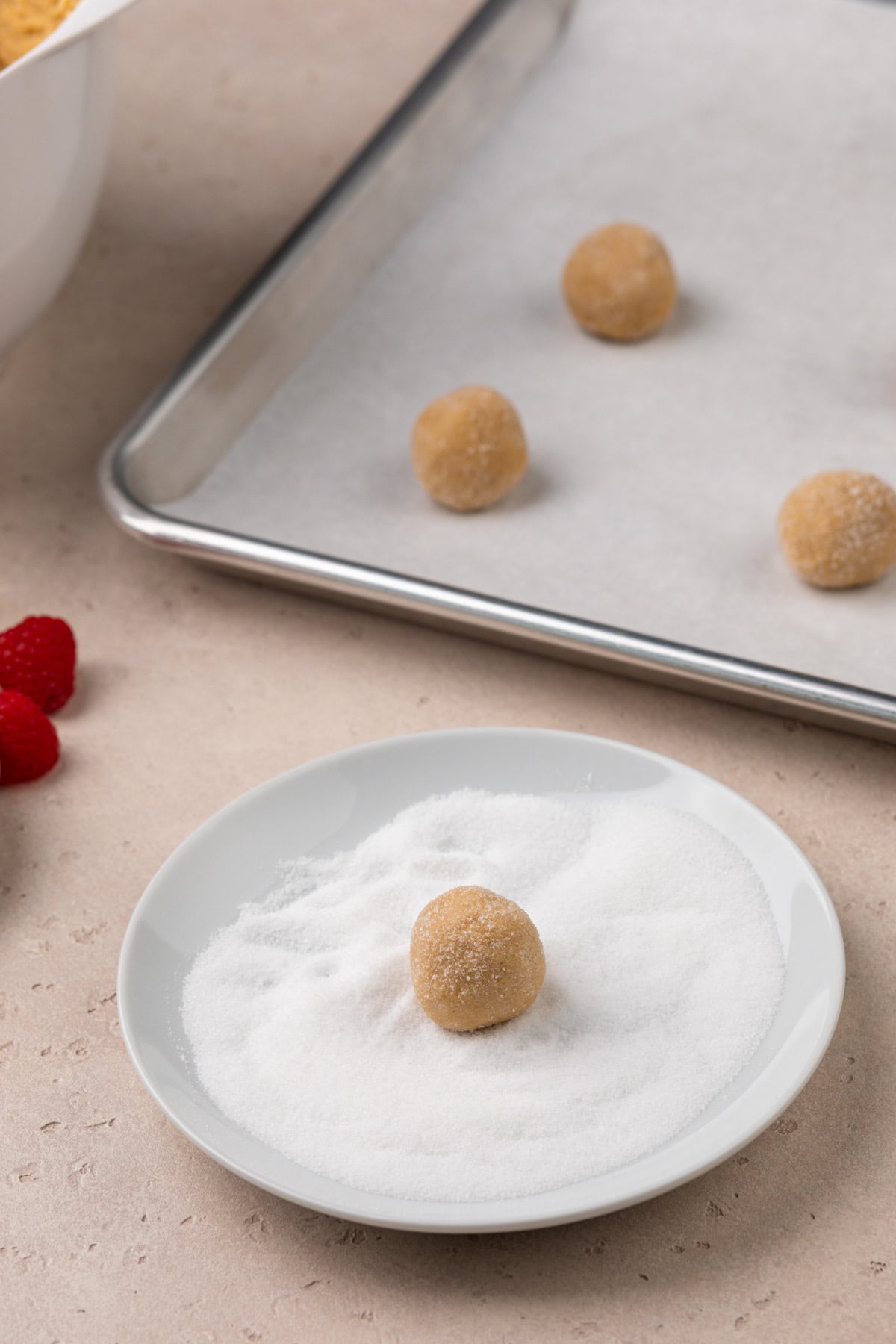 Rolling balls of peanut butter cookie dough in granulated sugar.