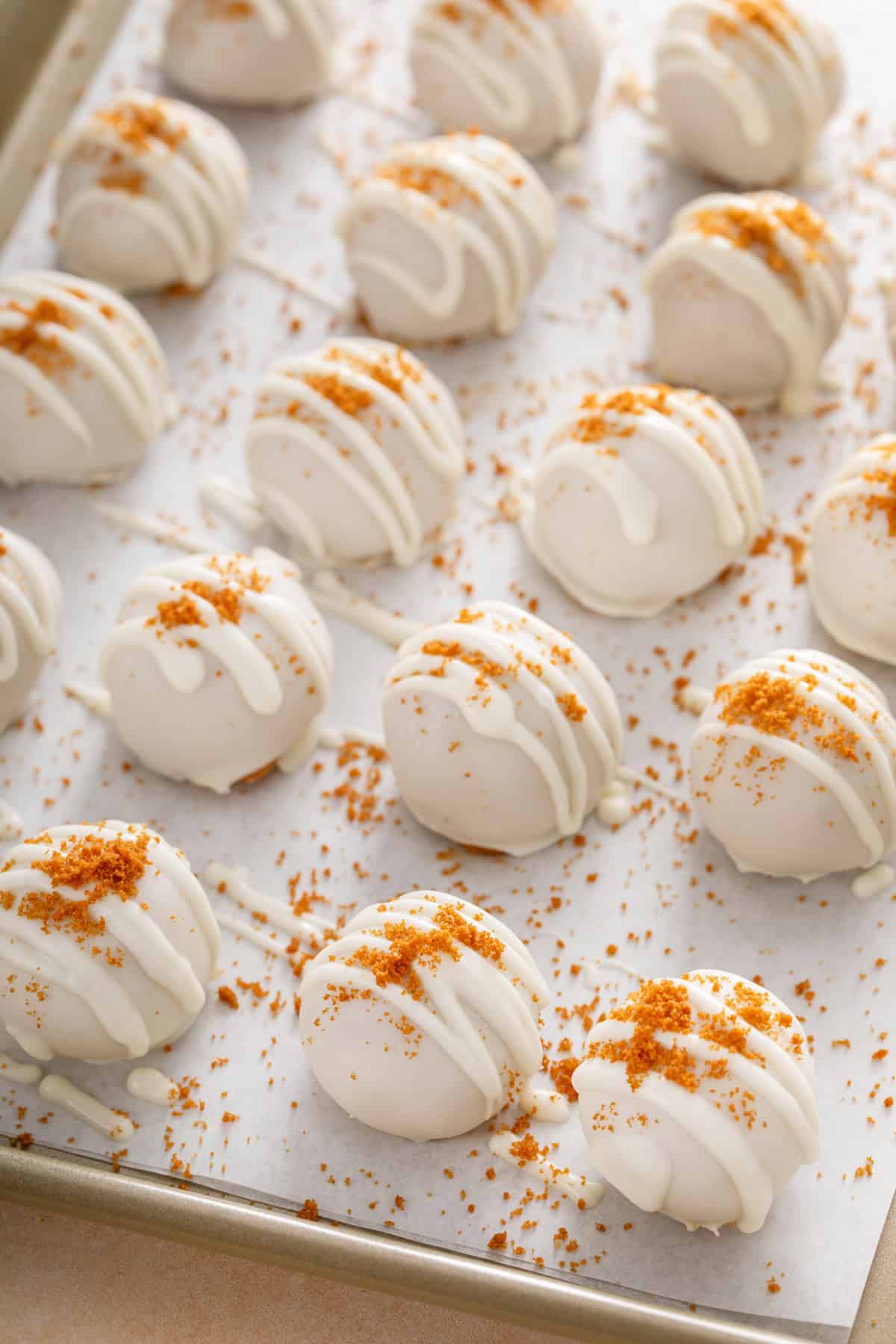 Garnished pumpkin cheesecake balls setting up on a baking sheet.