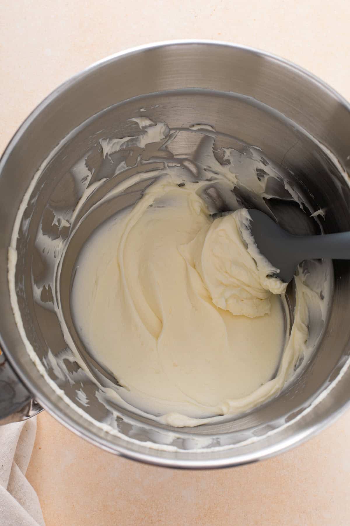 Cream cheese and powdered sugar beaten in a metal bowl.