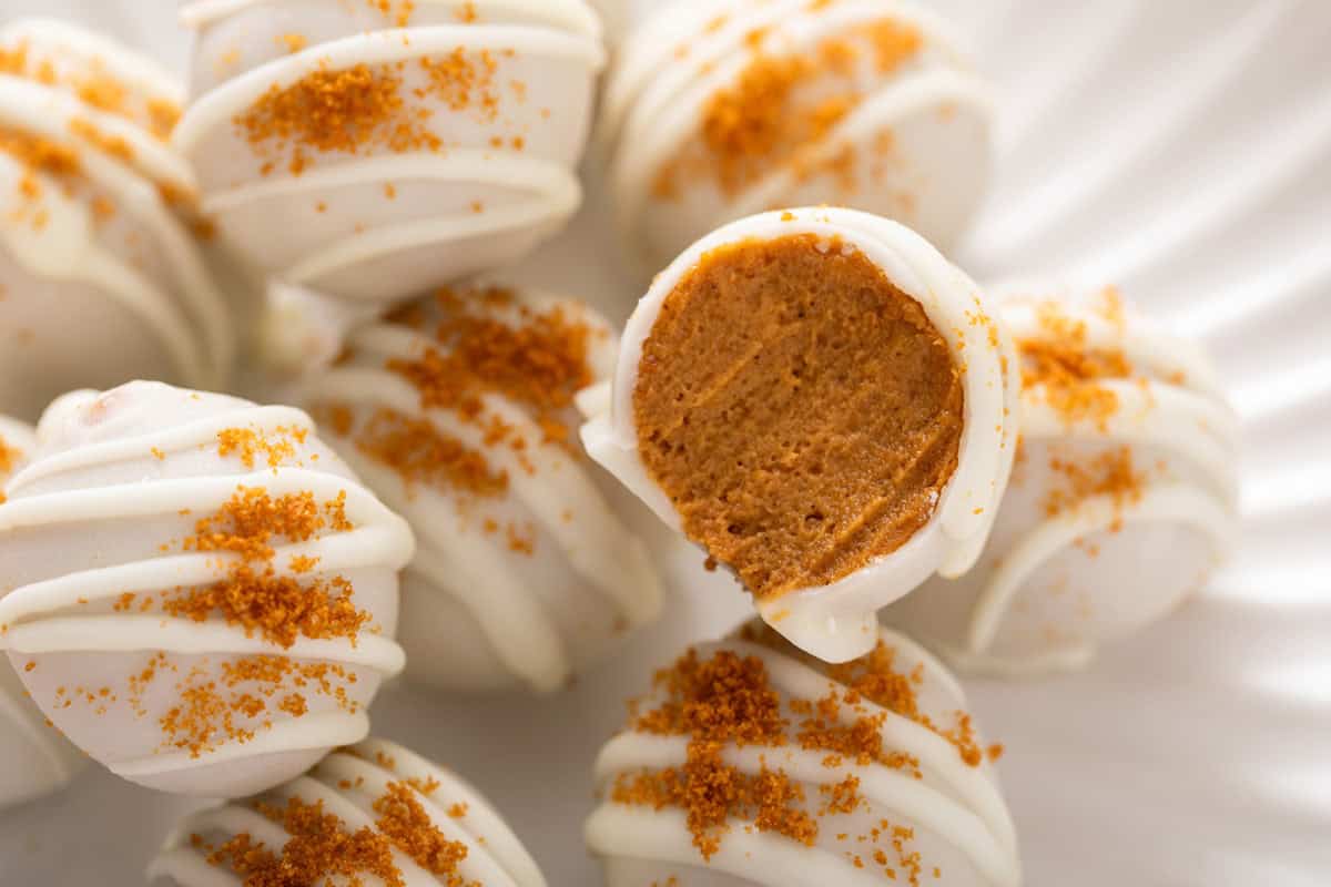 Halved pumpkin cheesecake ball set on a platter with more of the cheesecake balls.