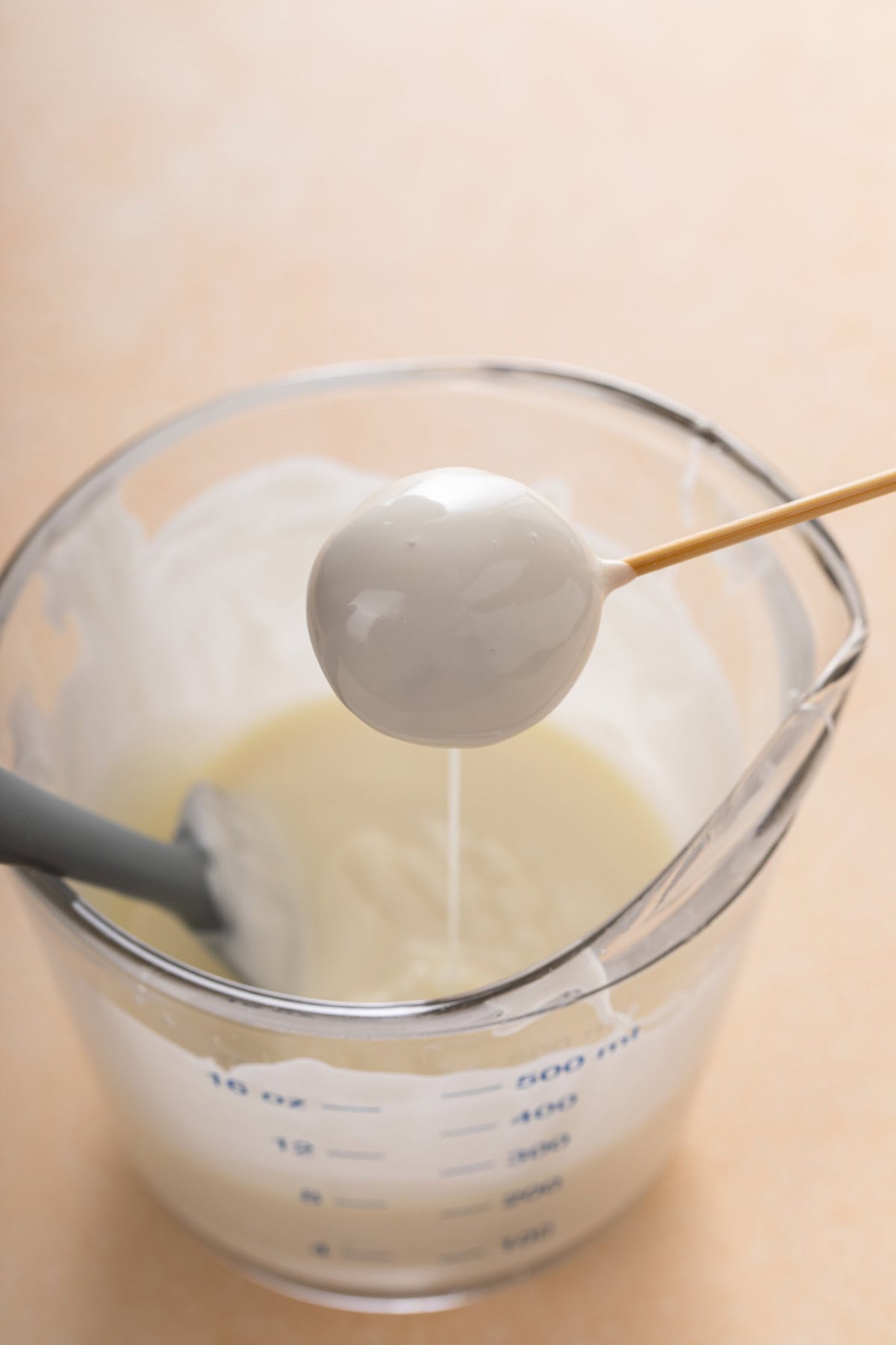 Coating a pumpkin cheesecake ball in white chocolate coating.