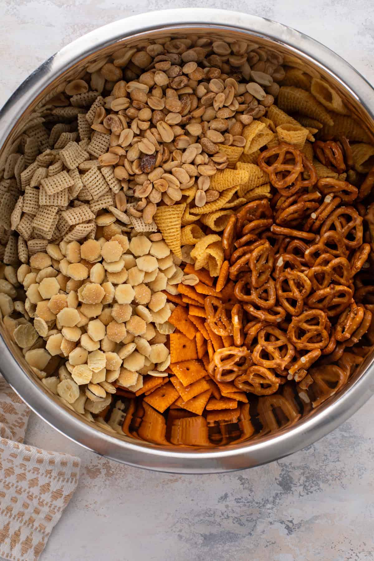 Crunchy snacks for ranch chex mix added to a large metal bowl.