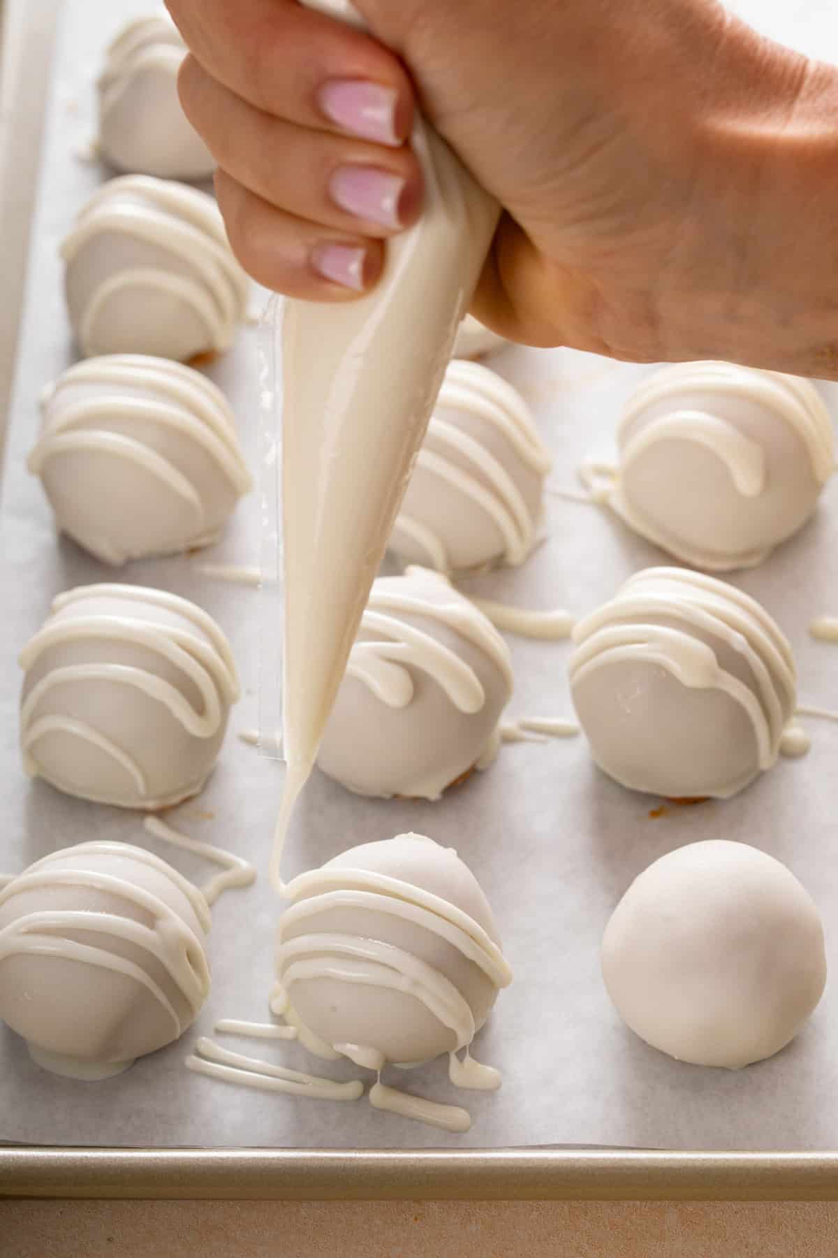 Drizzling tops of pumpkin cheesecake balls with candy coating.
