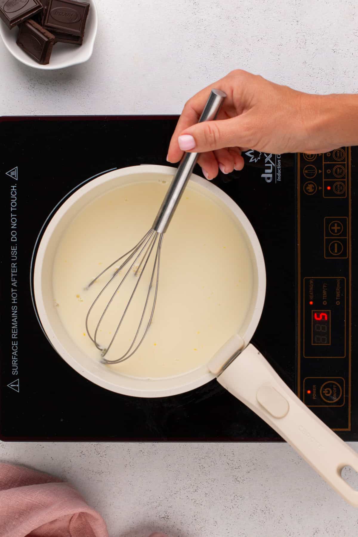 Chocolate pudding base being whisked on a burner.