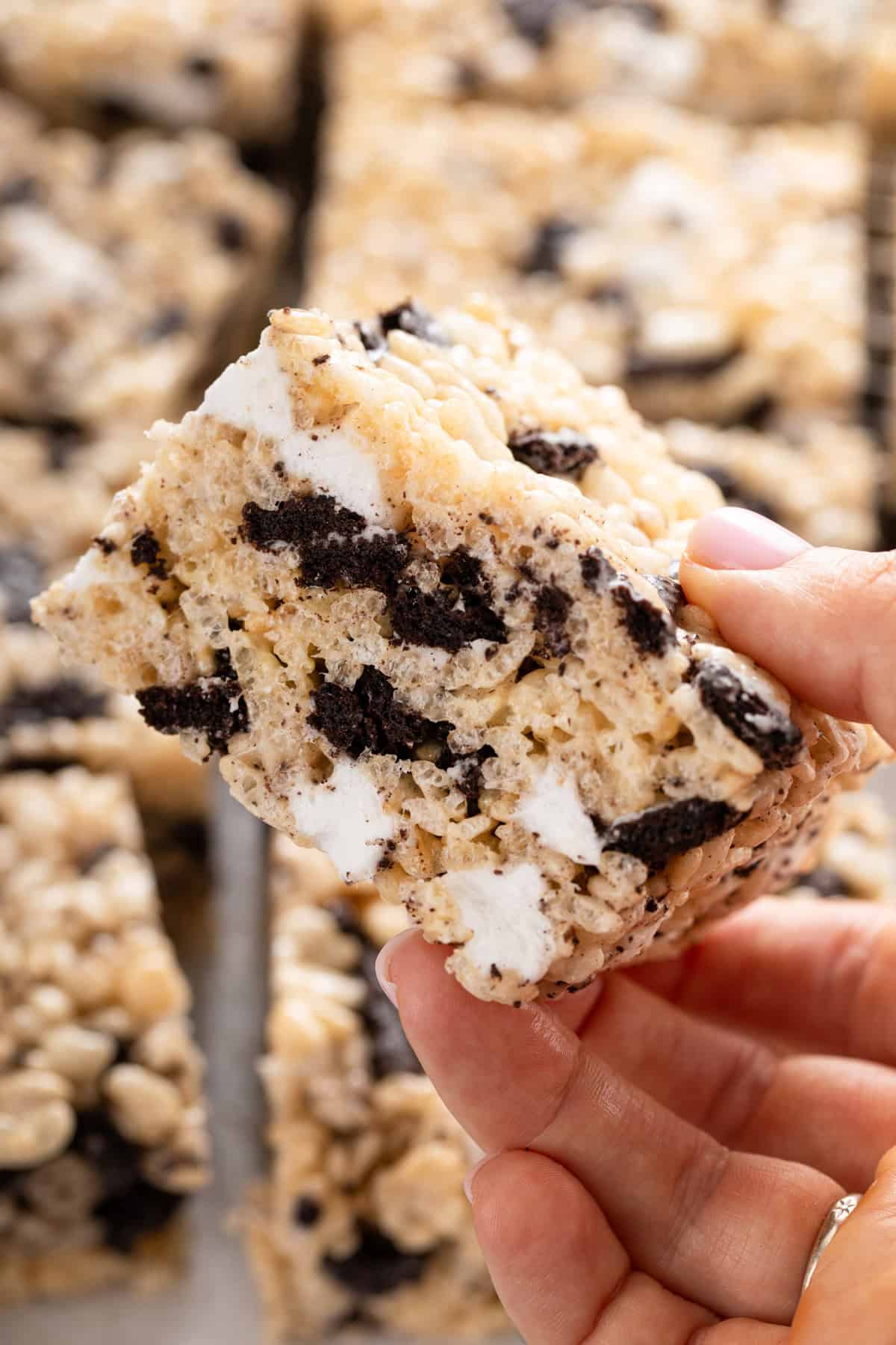 Person holding up a sliced oreo rice krispie treat to the camera.