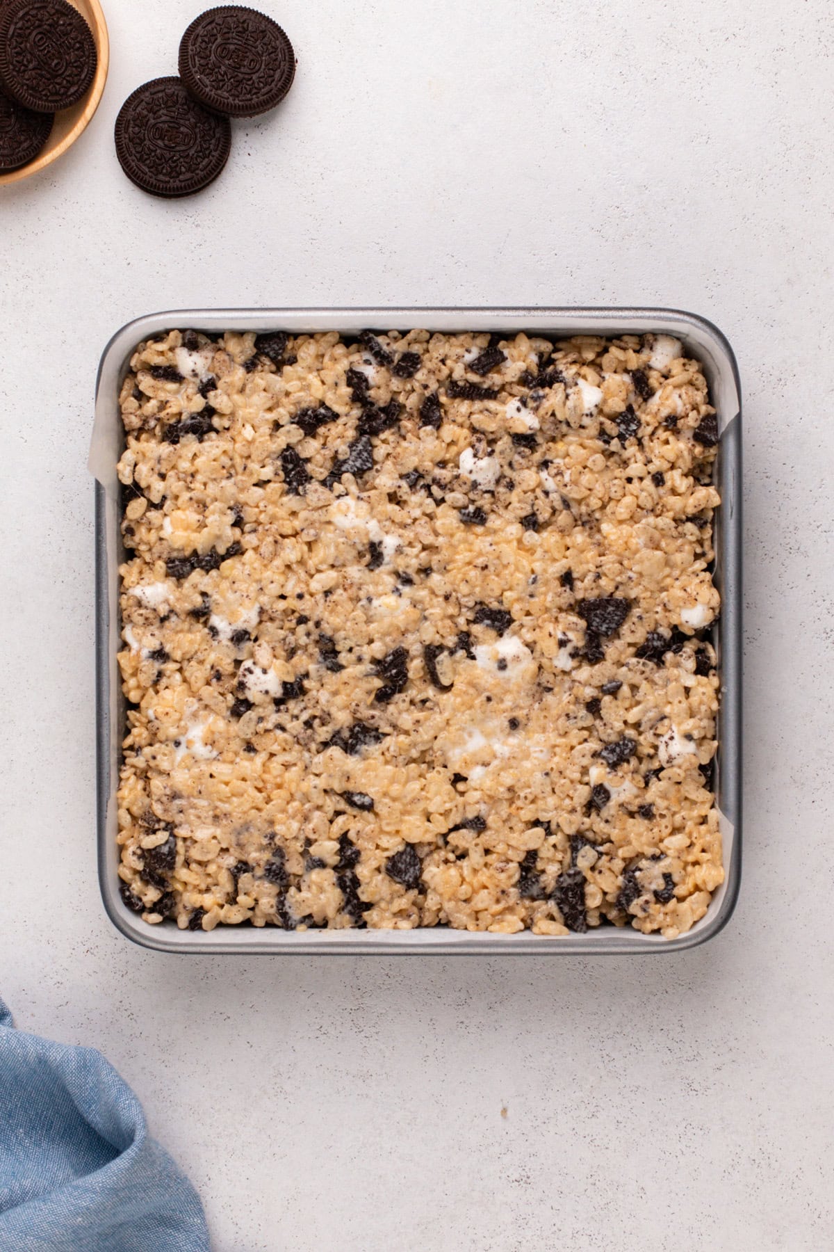 Oreo rice krispie treats pressed into a square pan on a countertop.