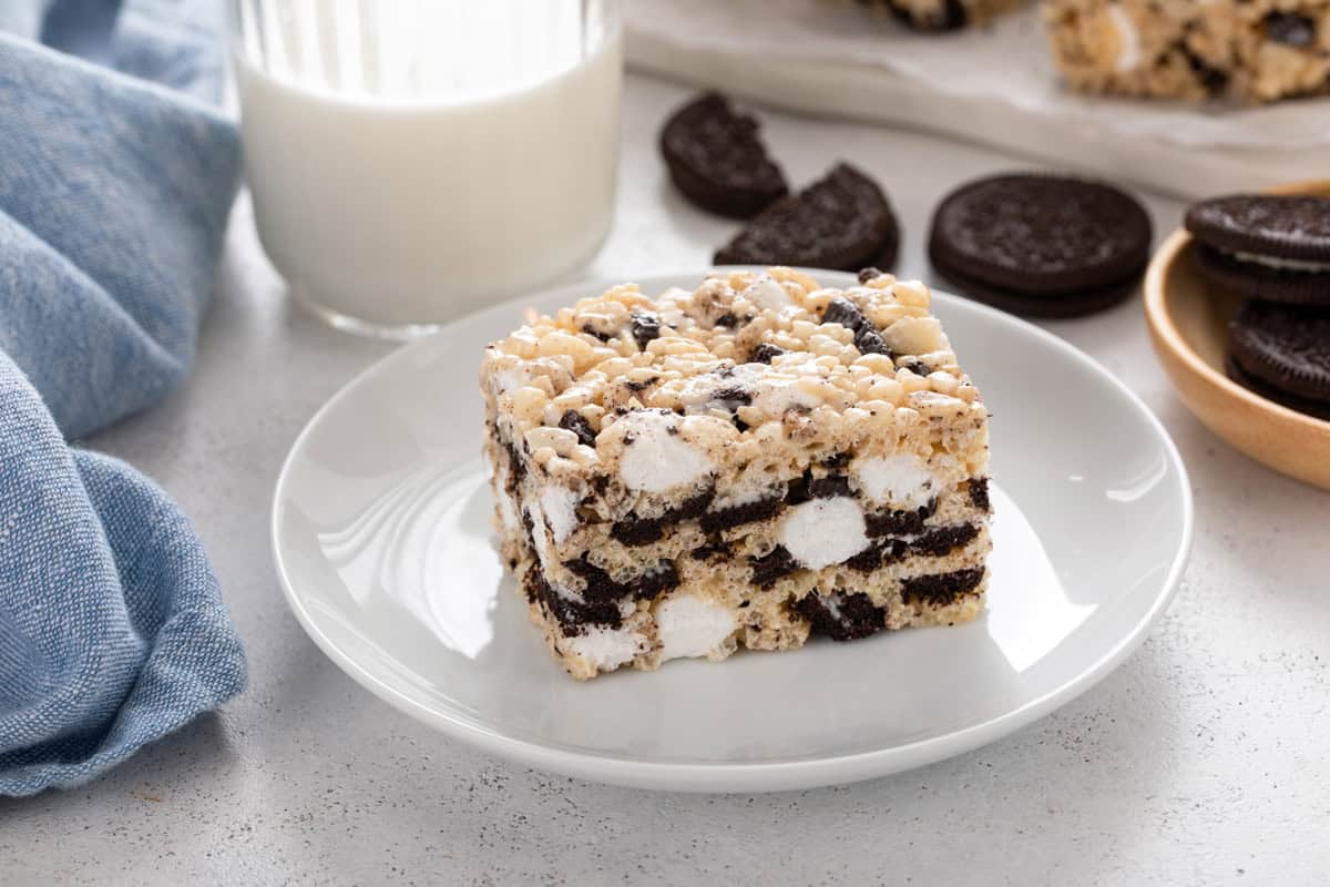 Oreo rice krispie treat on a white plate with a glass of milk in the background.