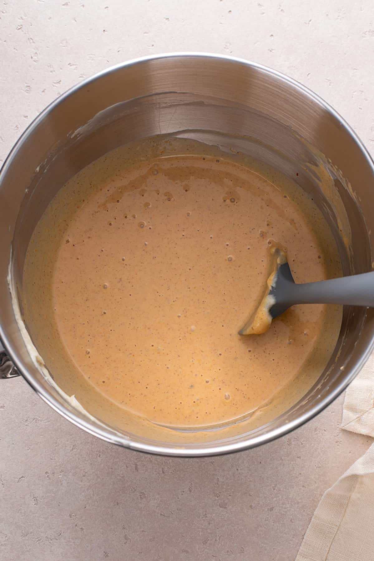 Pumpkin cheesecake pie filling mixed in a metal bowl.