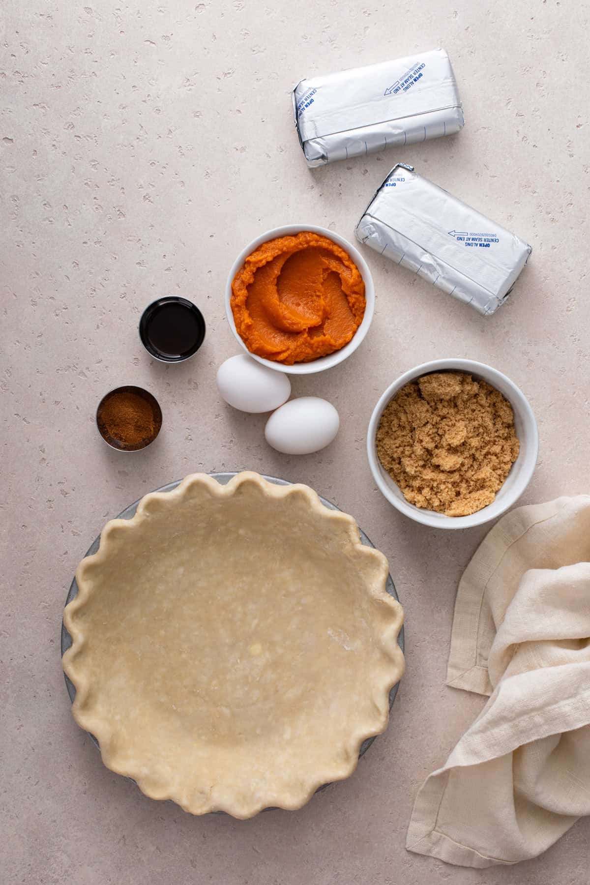 Ingredients for pumpkin cheesecake pie arranged on a countertop.